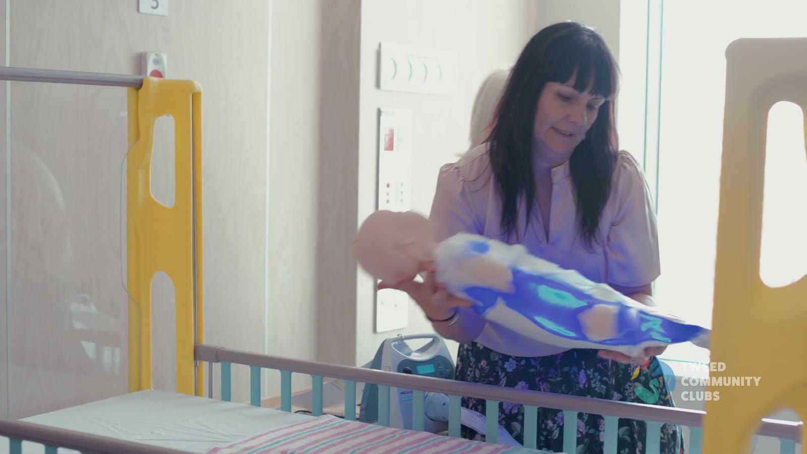 A staff member demonstrates the glowing UV baby blanket beside a cot at the Tweed Hospital